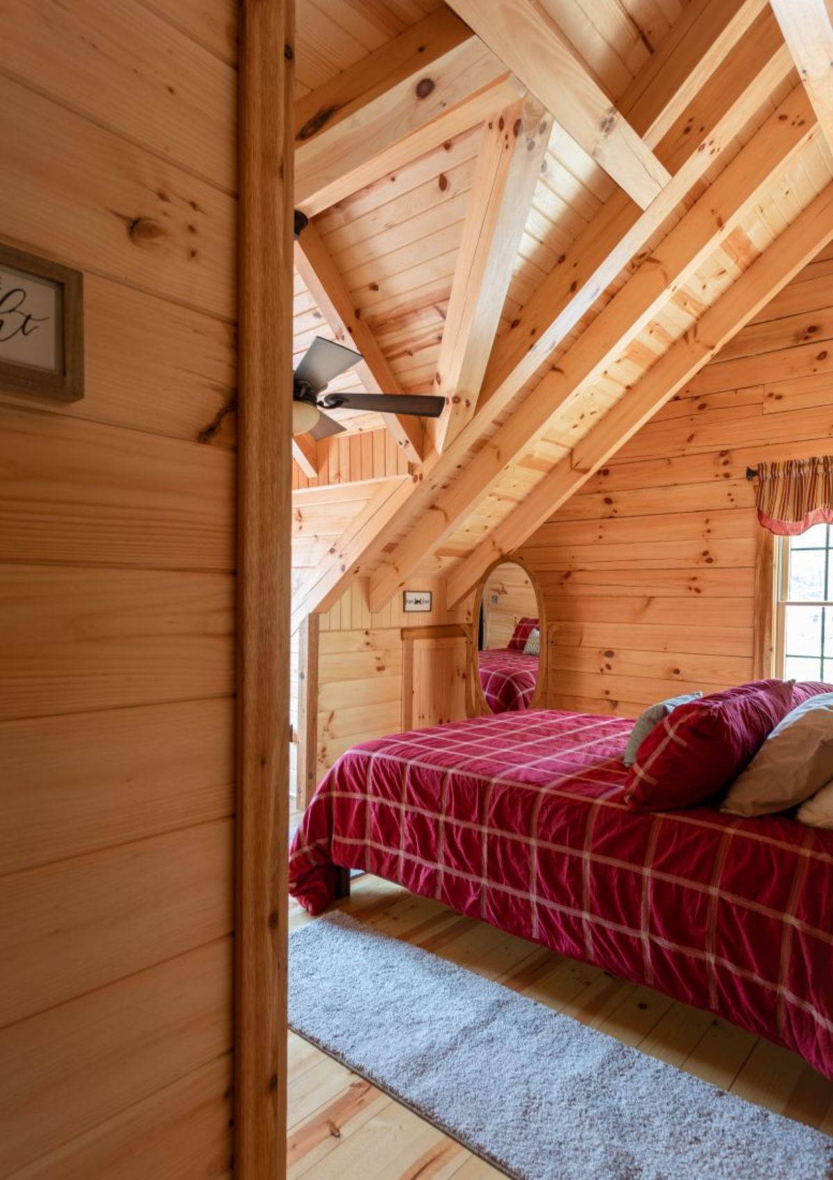 red striped bedding on bed under log cabin loft eaves