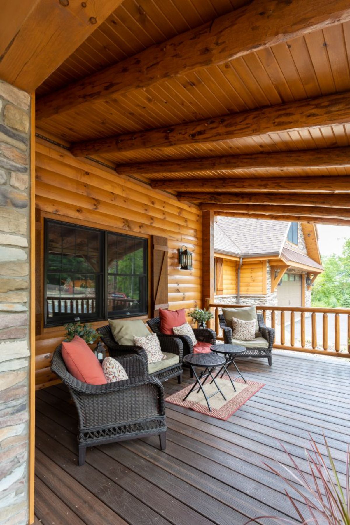 brown wicker chairs with ivory and red cushions on front porch of log cabin