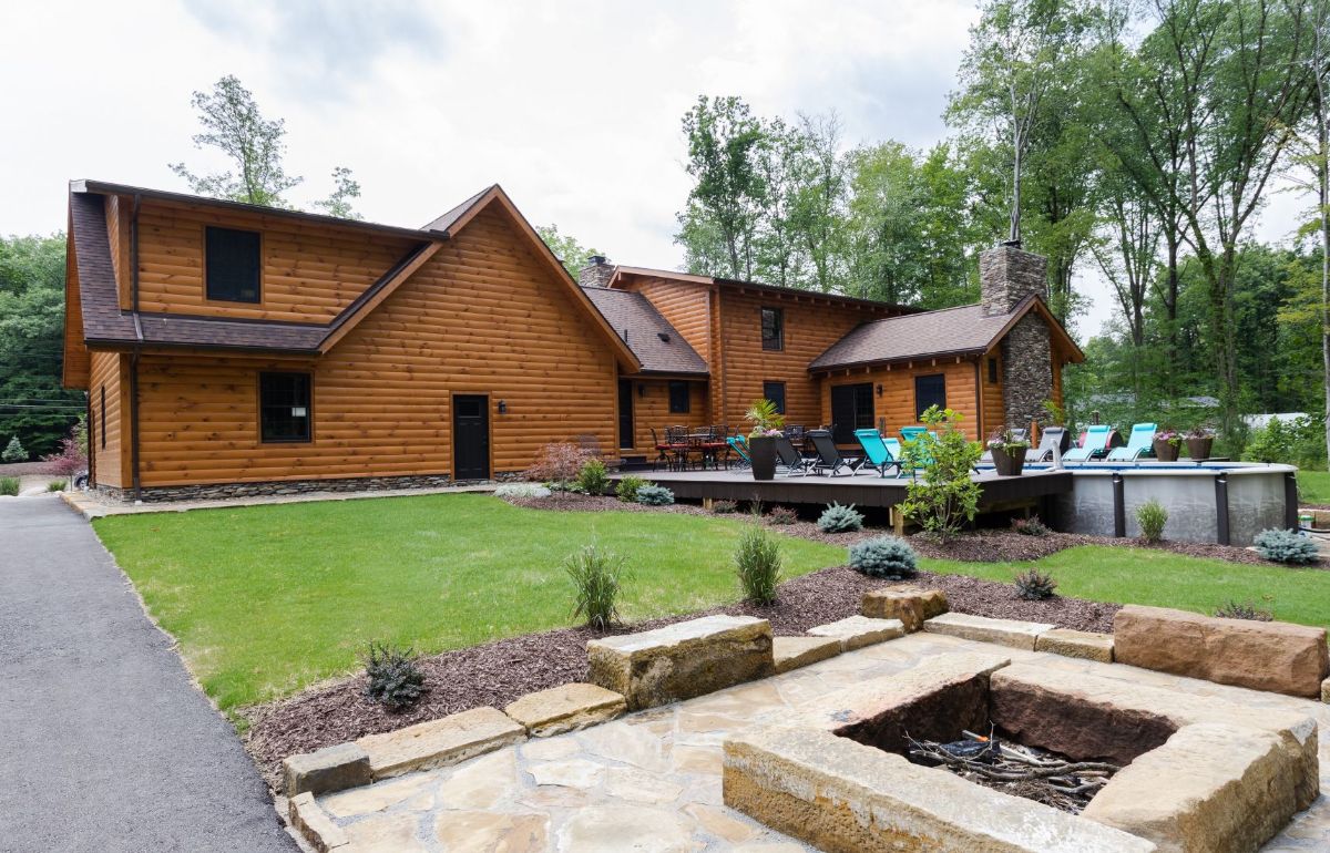 rock firepit on right of image with log cabin in background