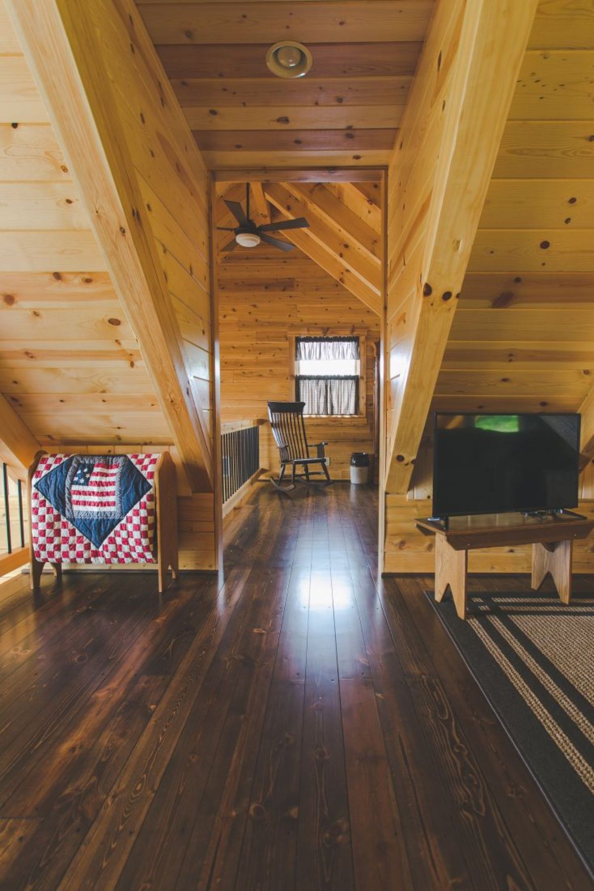 loft bedroom open door with TV on right and quilt on left