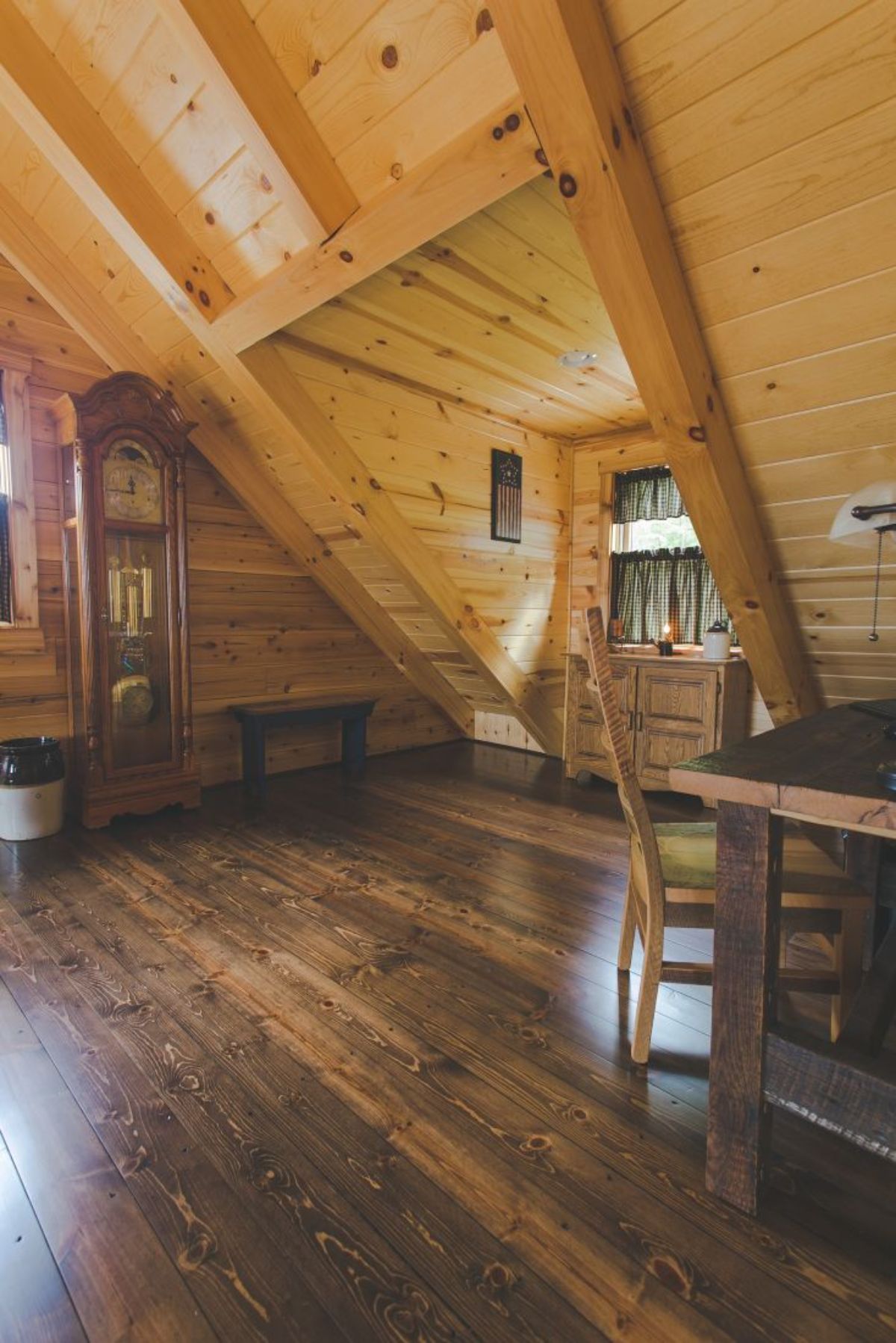 table on right side of log cabin dormer room with grandfather clock on left wall