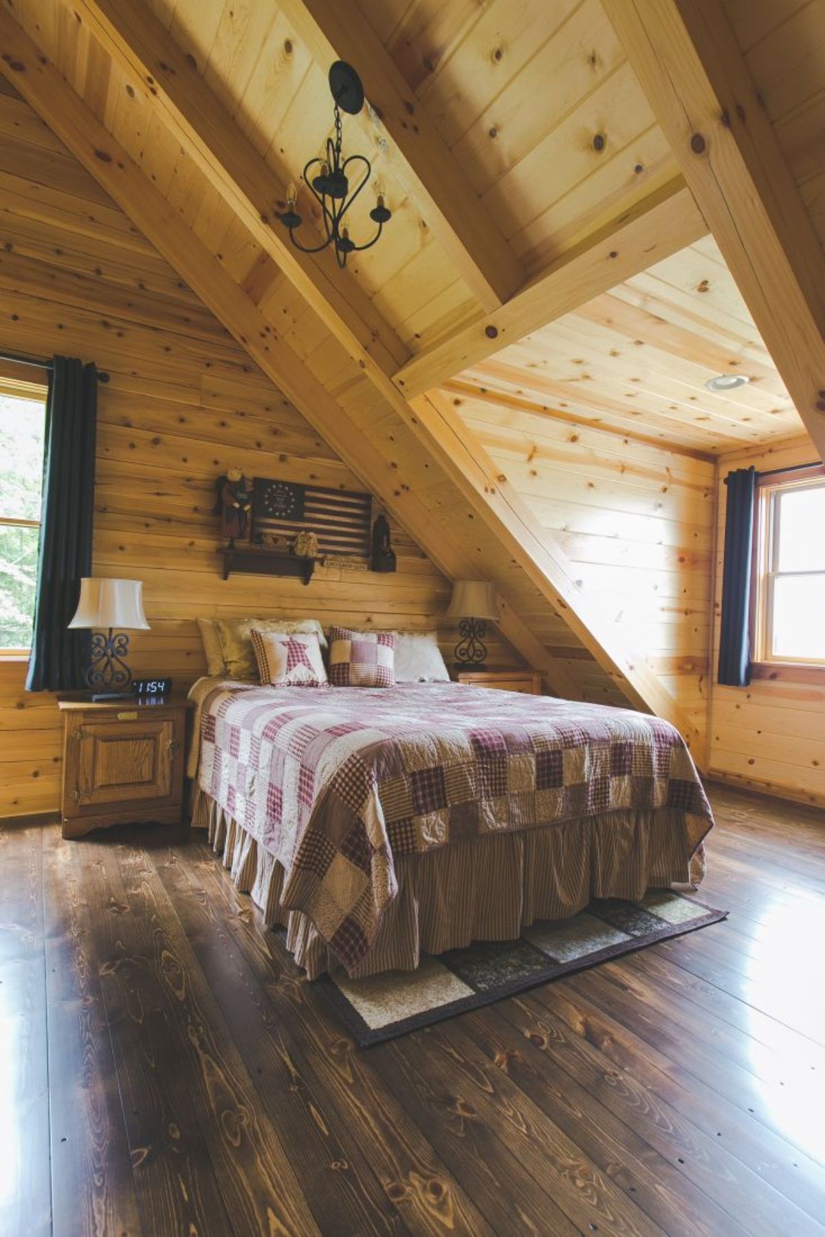 light clored bedding on bed against log cabin wall next to dormer window