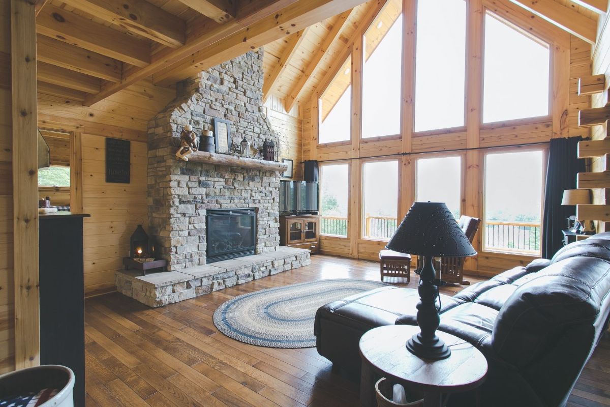 stone fireplace in left background with black leather sofa in foreground