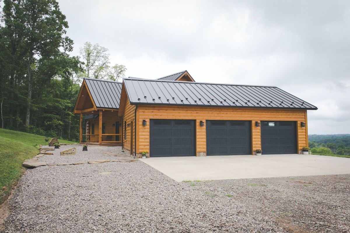 three car garage with green doors on side of log cabin