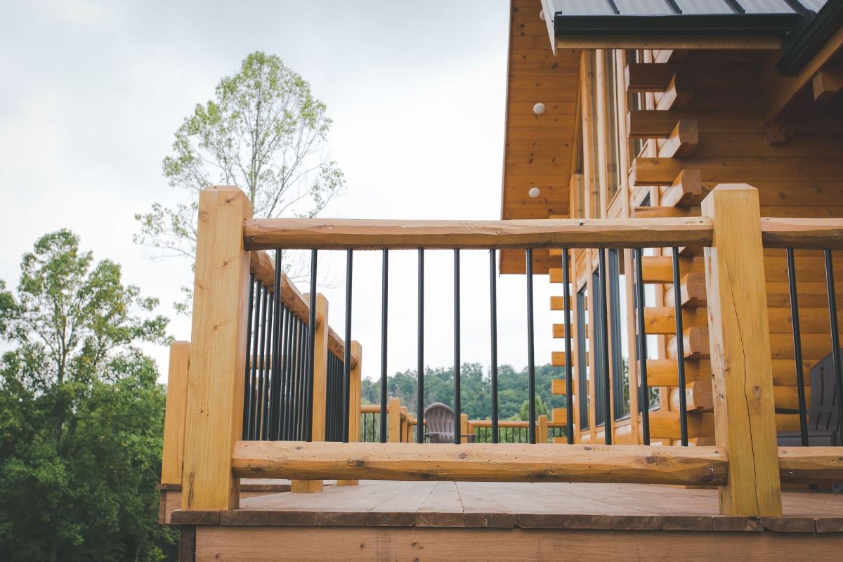 metal railing with log beams on deck of log cabin