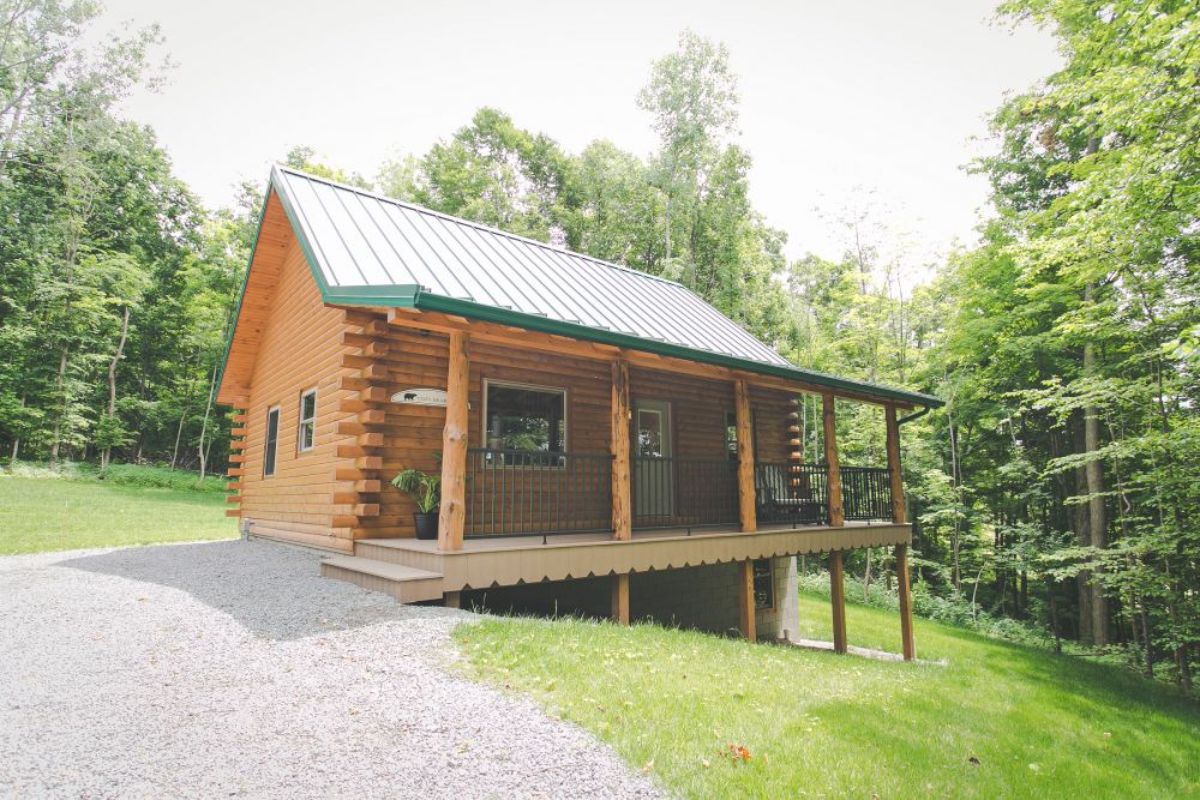 small log cabin on hill with covered porch