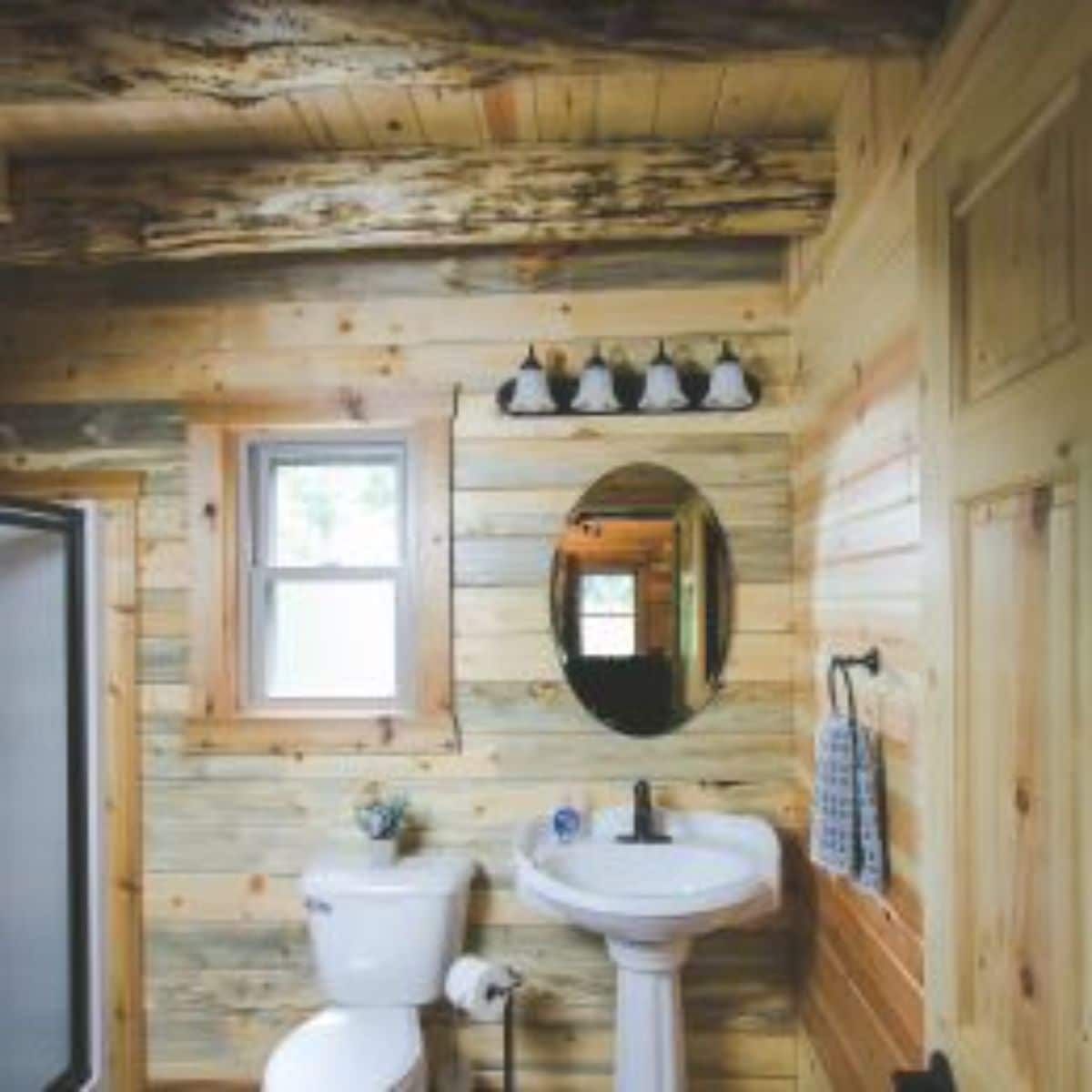 white toilet and sink against wall in log cabin