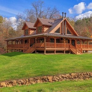 log cabin on hill with creek and rock wall on side of property