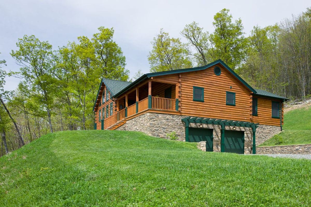 log cabin on hill with green roof and stone foundation