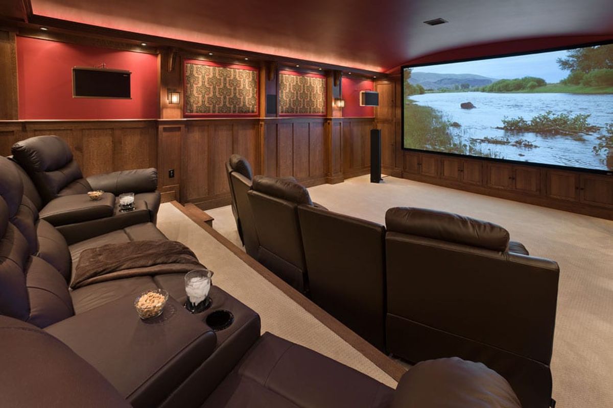 black reclining chairs in theater room of log cabin with red and wood walls