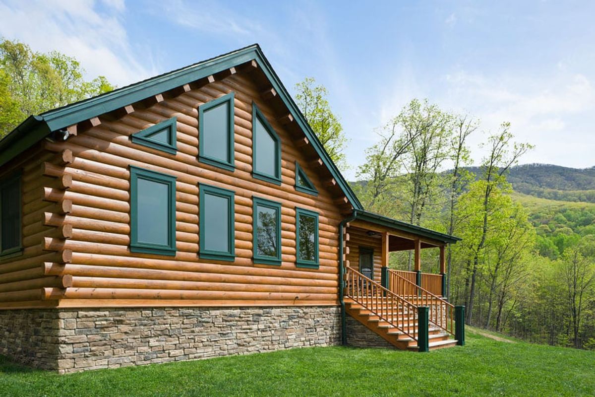 side of log cabin with green trim around great room windows