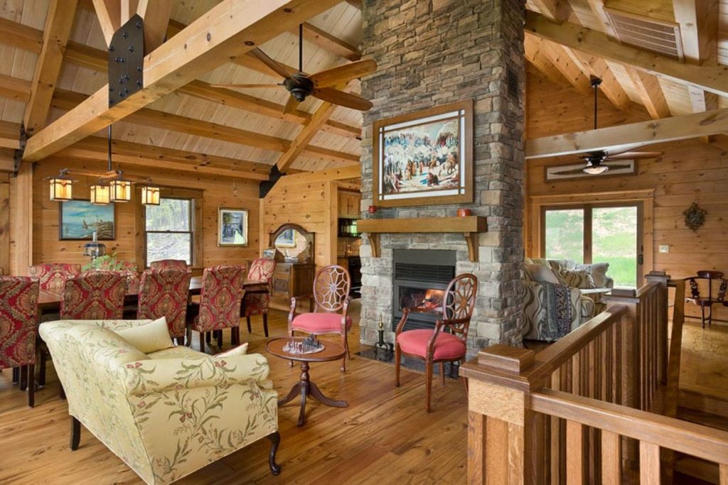 fireplace against wall with wood mantle and vintage chairs in front with red cushions