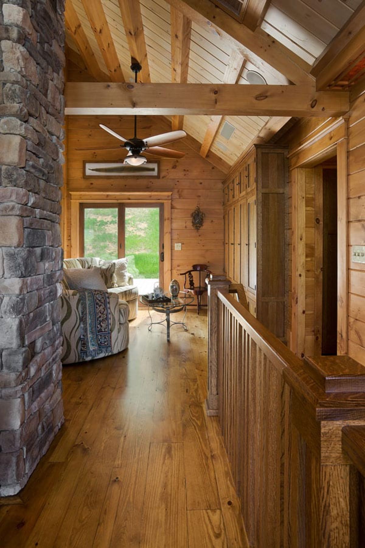 view into living area from hall by fireplace and stairs to lower level of home