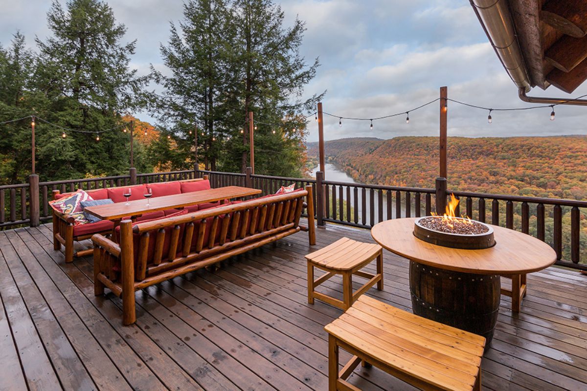 red cushions on outdoor wood seating with table and benches on right side of patio