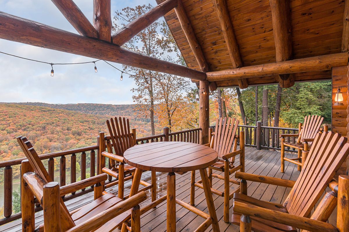 round table and wood chairs underneath log cabin porch