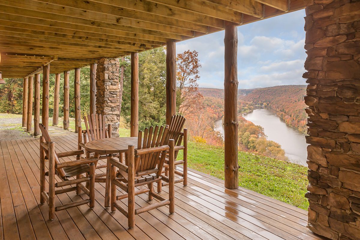 view of mountains and river in the background off log cabin deck