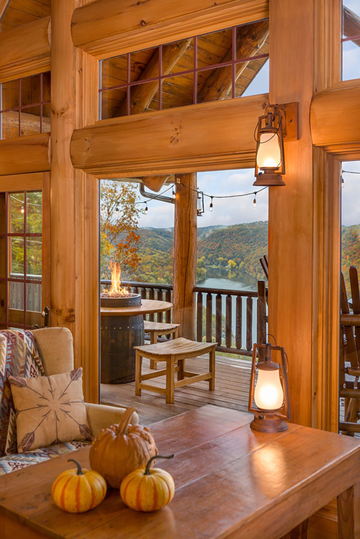 view out of log cabin window to deck overlooking woods and river