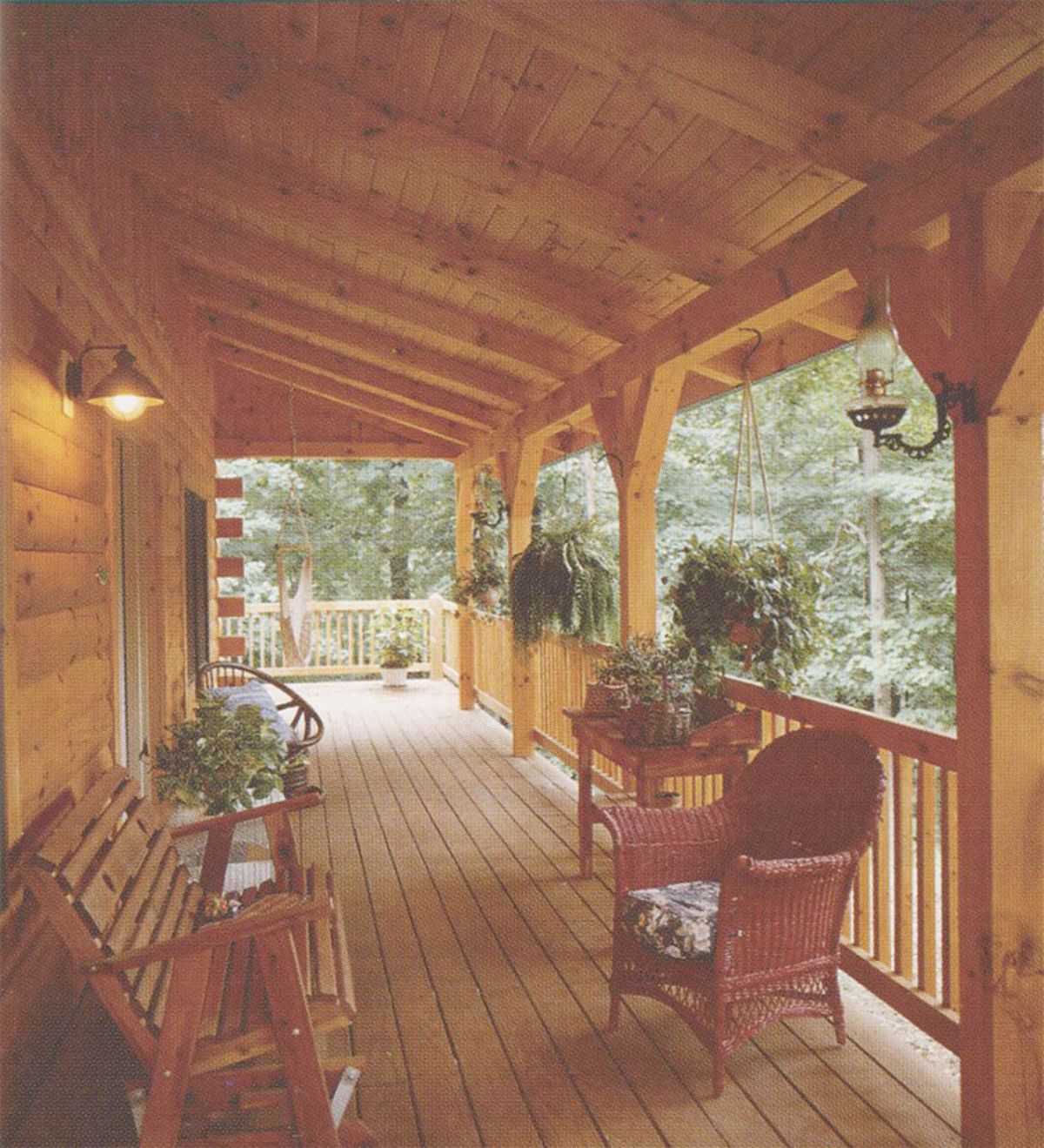 front porch of log cabin with wicker chair against rail and wood porch swing against wall