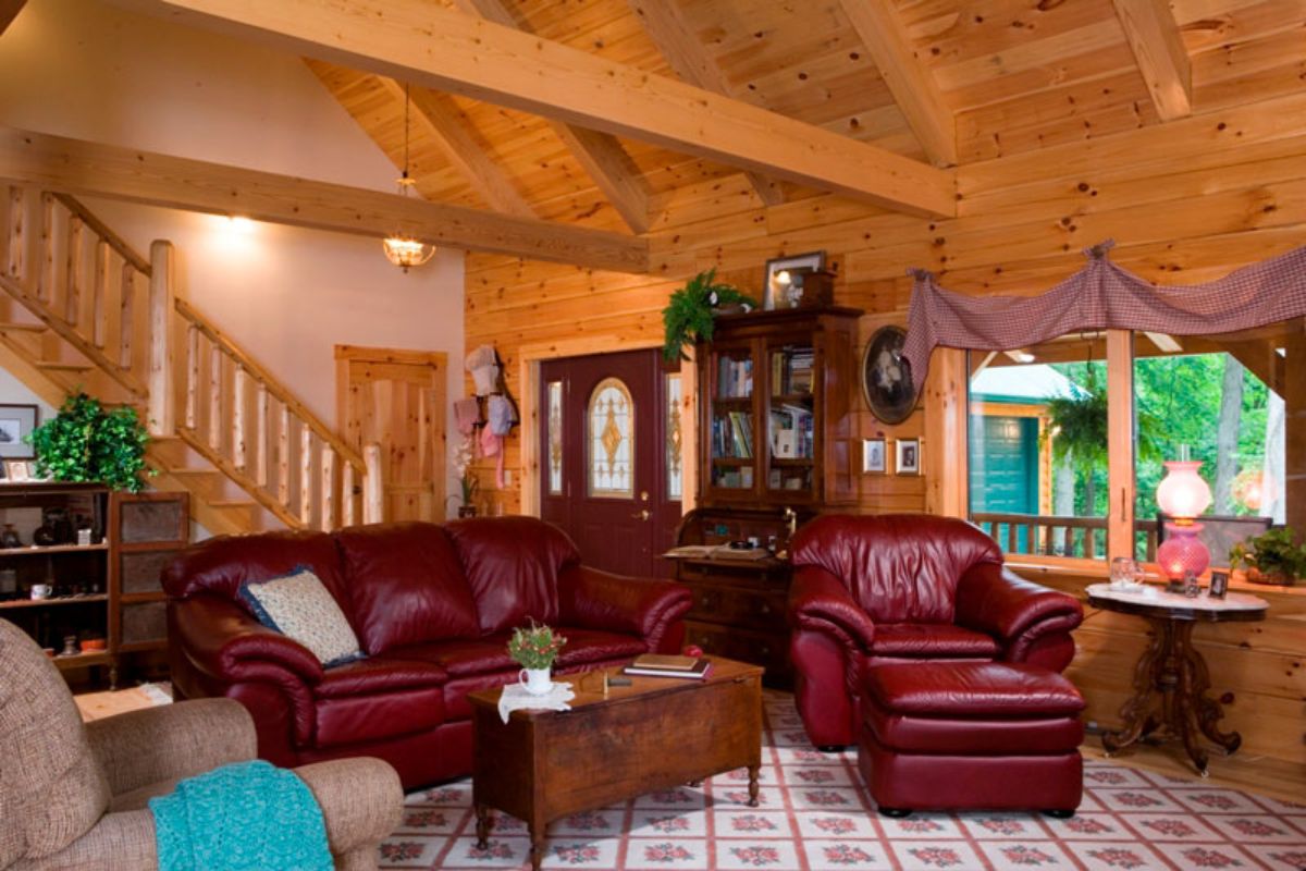 red leather sofas on white rug with stairs to second floor and front door in background
