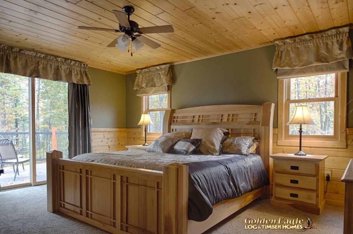 light wood bed with dark gray bedding against wood and green wall