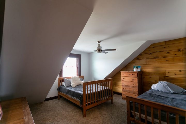 bed beneath white wall dormer window in cabin