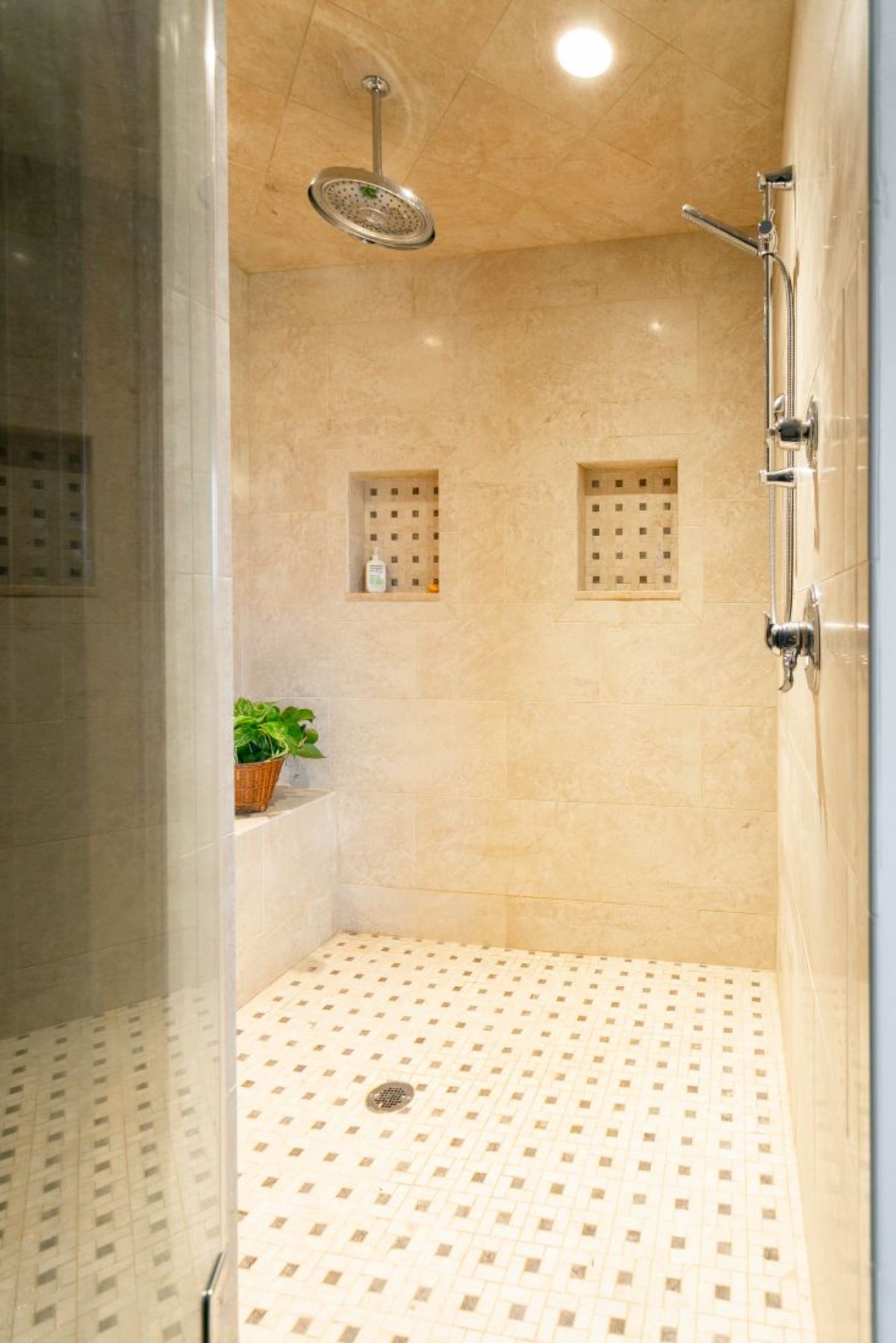 large tiled shower with cream brown and white tile in cubbies on wall