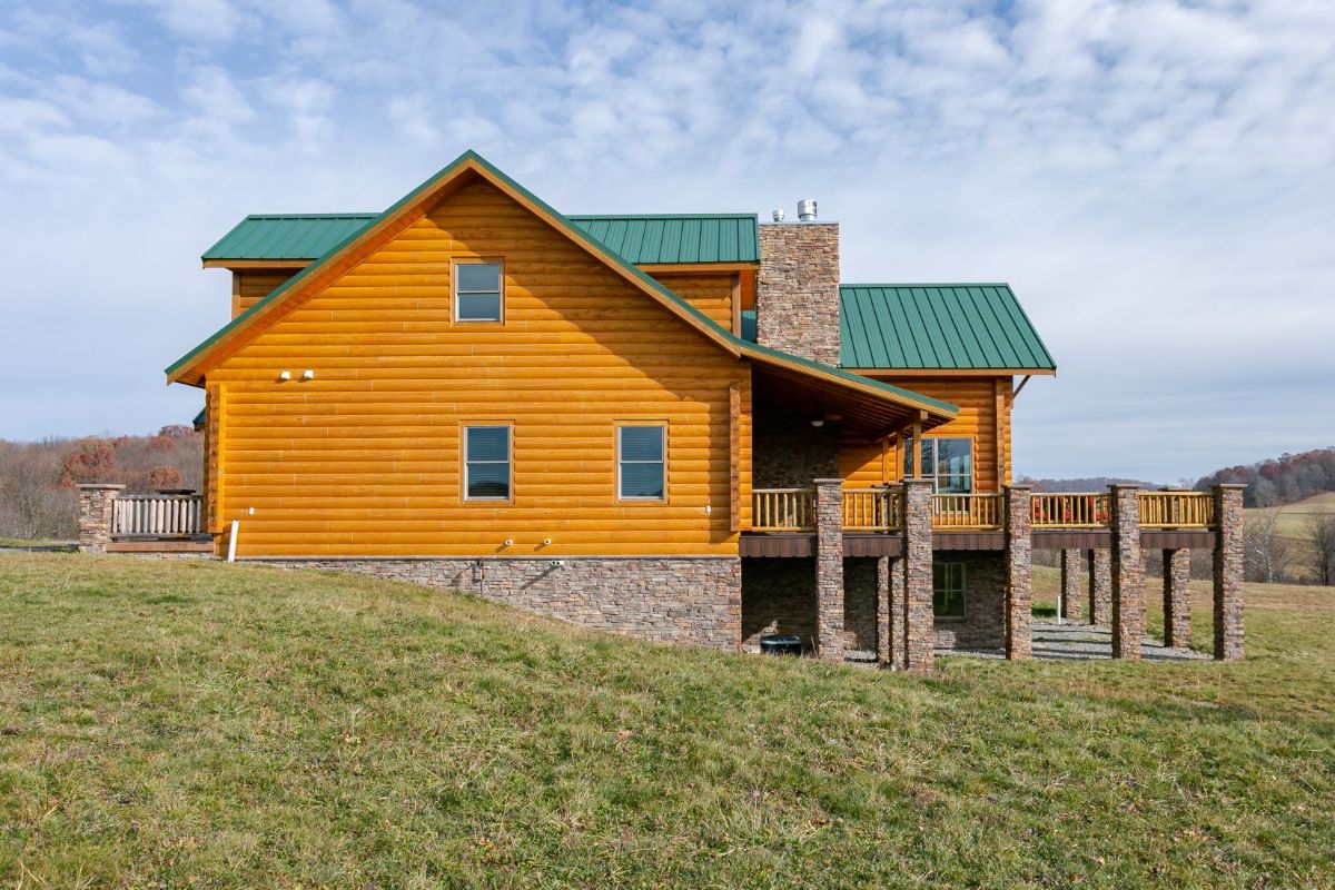 side of log cabin with three windows and green roof