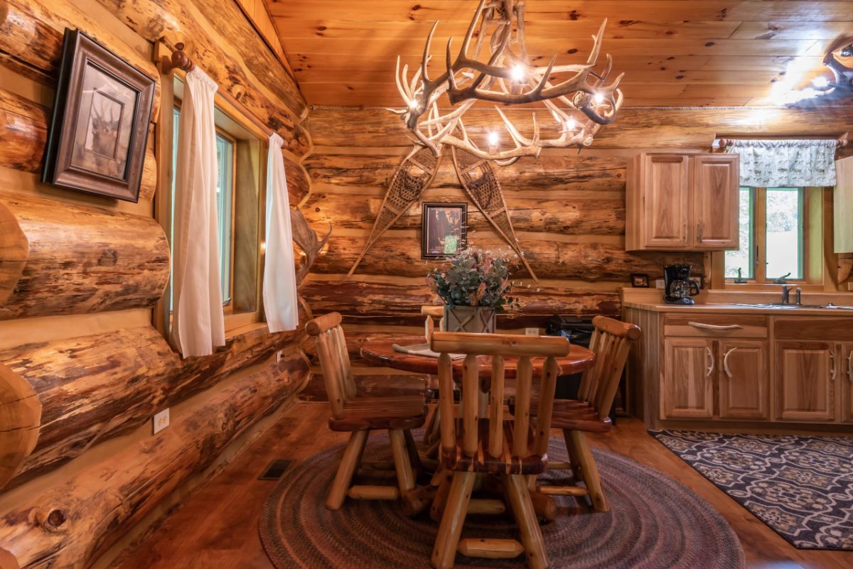 dining table underneath antler chandelier in log cabin