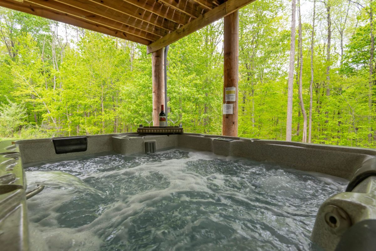 hot tub bubbling water in corner or porch with trees in view behind tub
