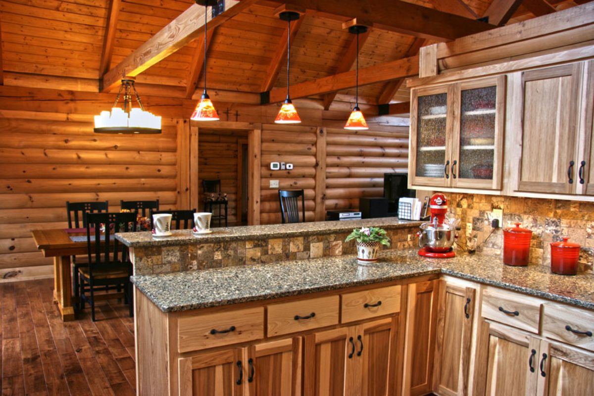 light wood cabinets beneath granite countertop with wood table in background by open door