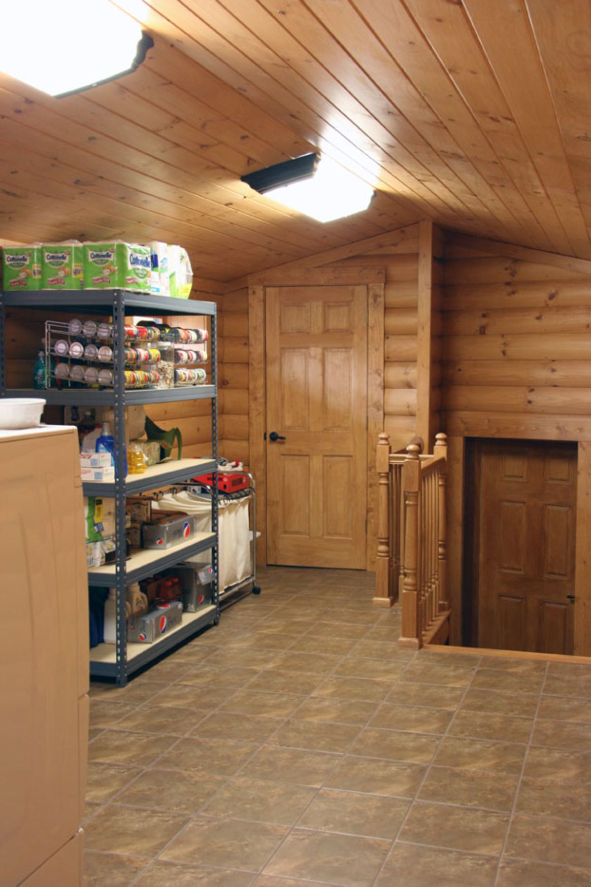 storage cabinets on left and stairs with door on right of log cabin attic