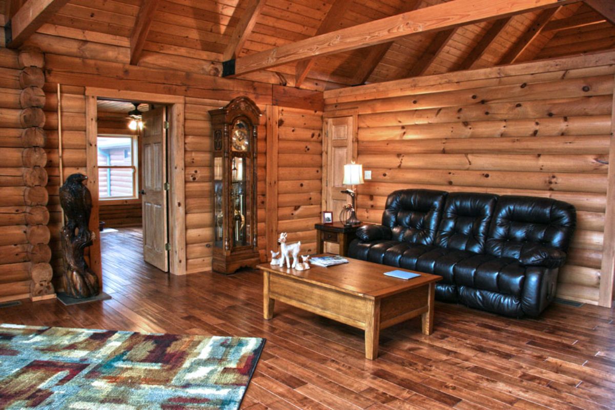 black leather sofa underneath log cabin open beams