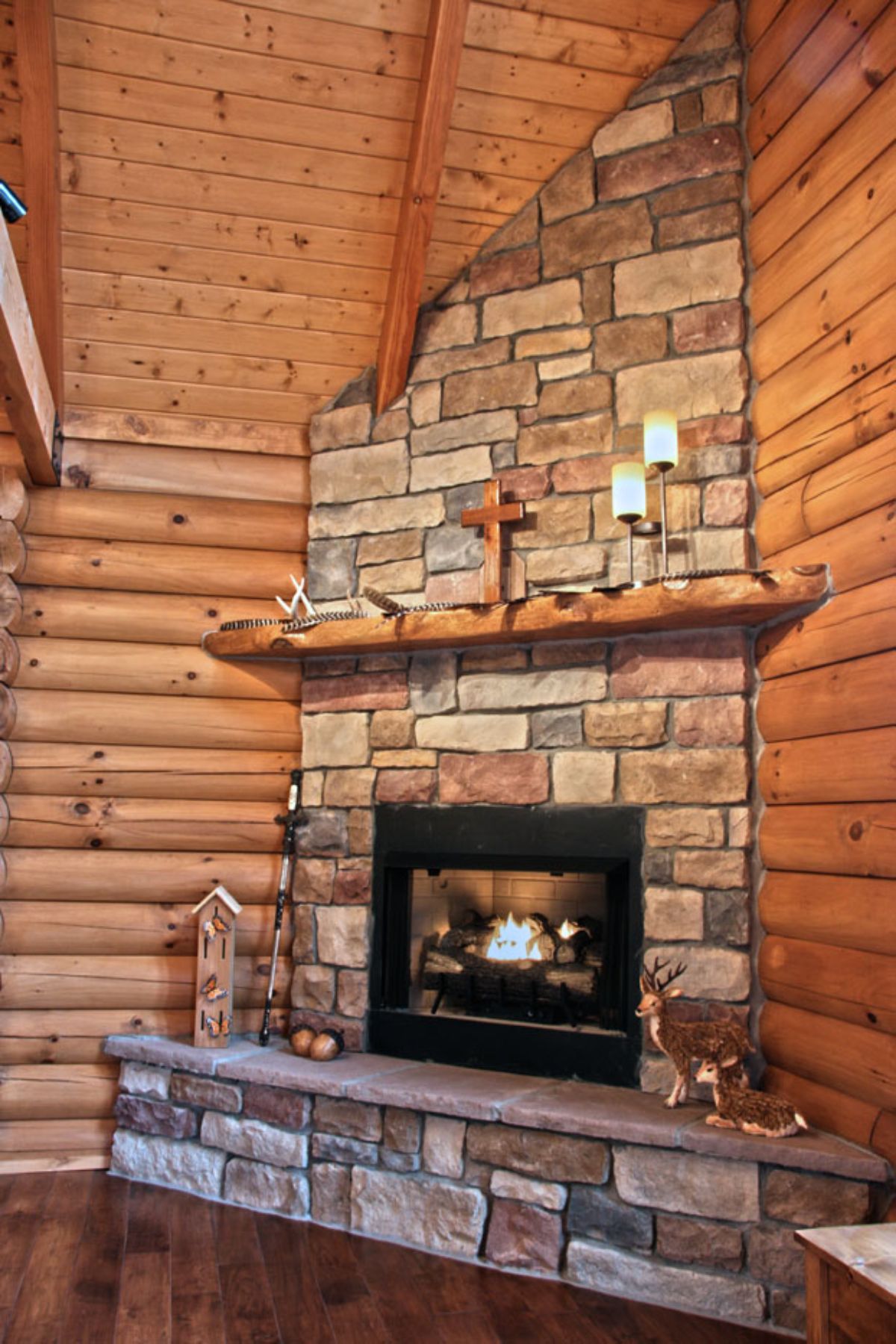 stone fireplace in corner of log cabin room