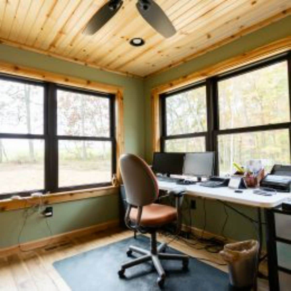 desk against wall of windows with ceiling fan above