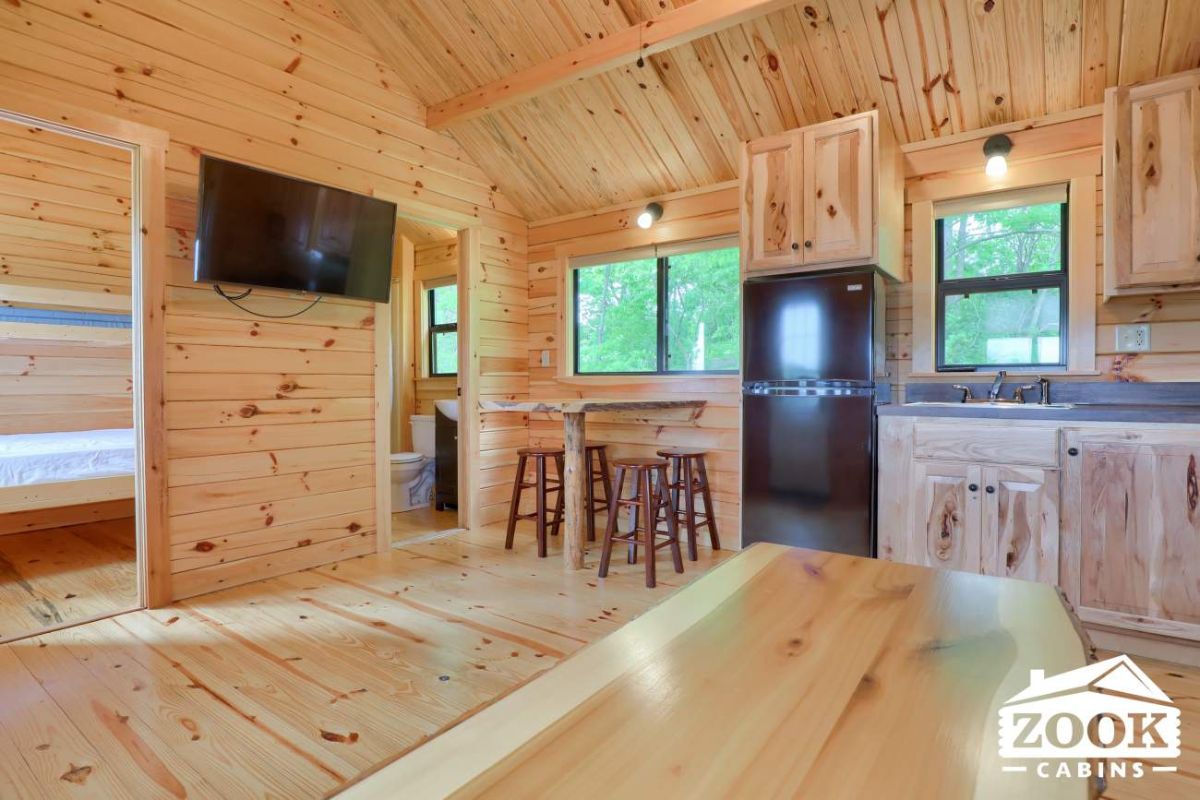 kitchen and dining space to the side of log cabin with black refrigerator