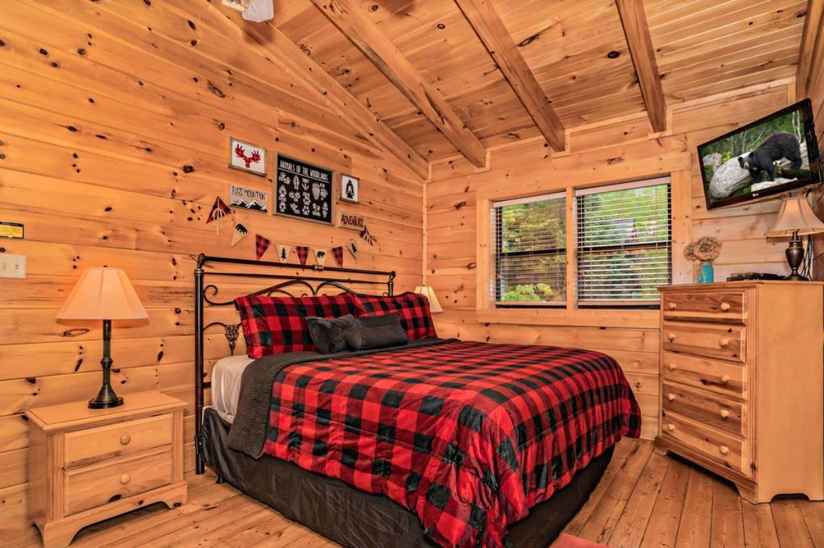 black and red buffalo plaid bedding on bed with black metal frame in log cabin top bedroom