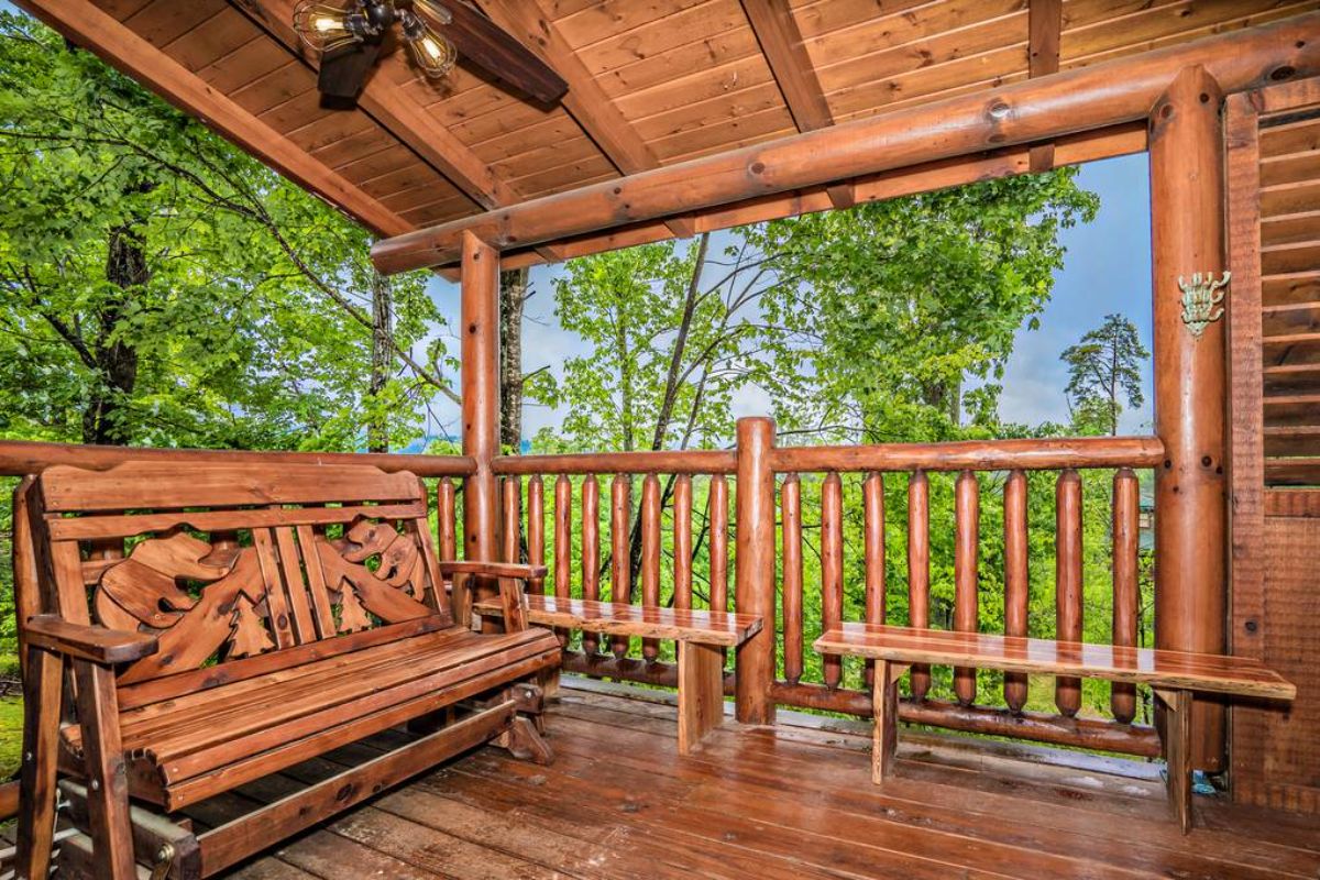 wooden porch swing on covered porch with ceiling fan above swing