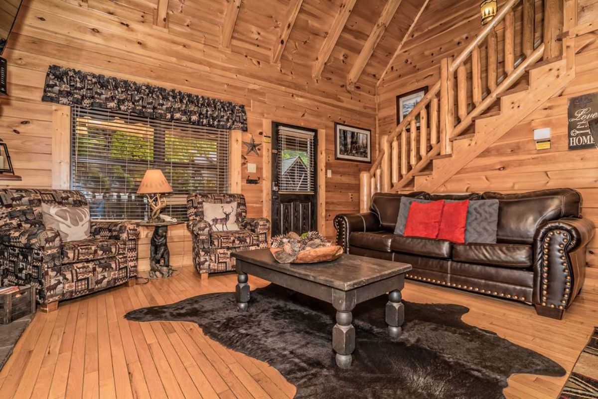 wooden coffee table on bear rug in middle of log cabin living room floor