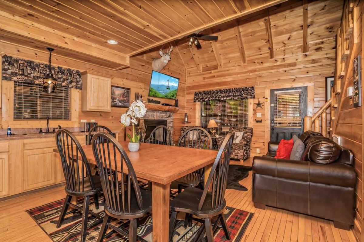 view into log cabin living room from behind dining table with dark wood chairs