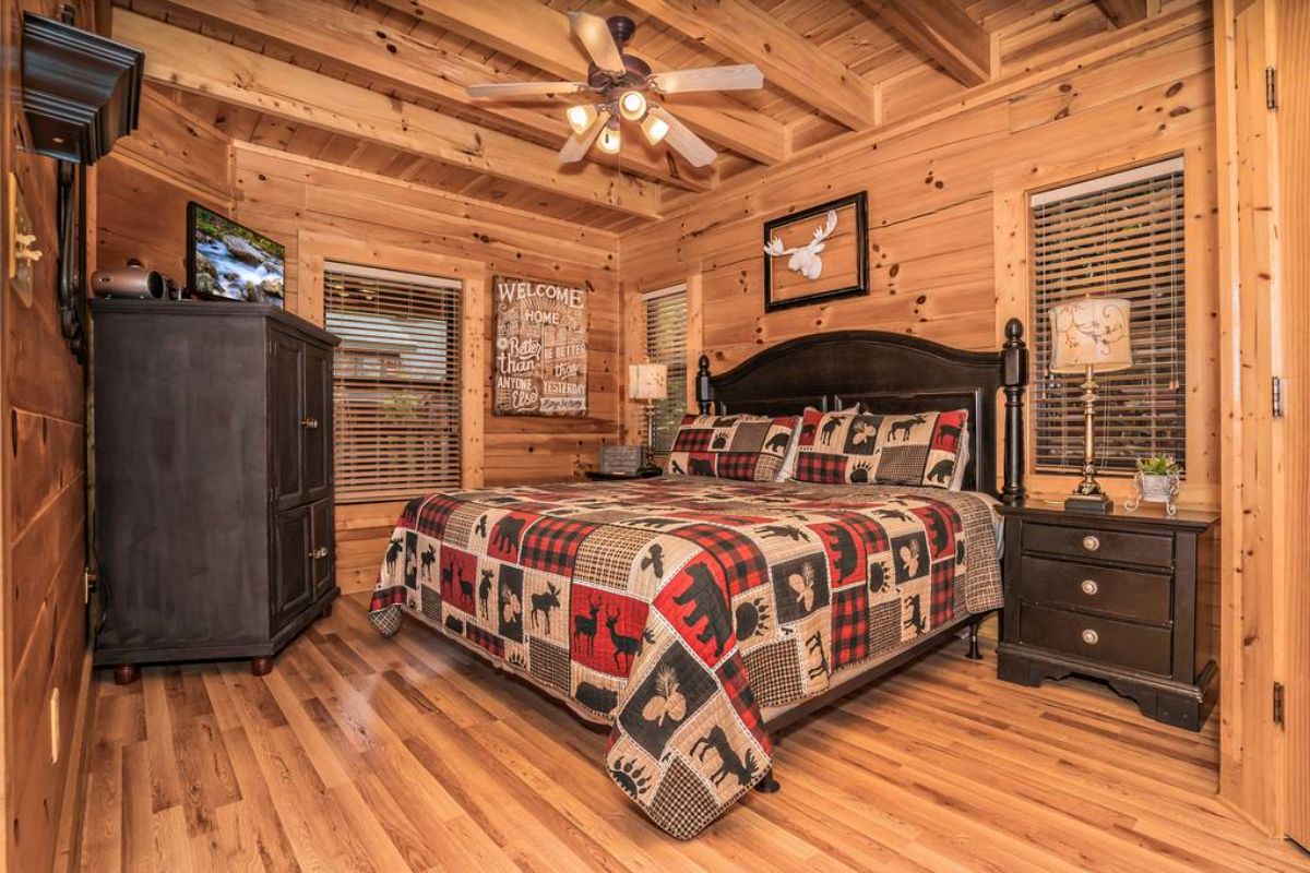 rustic qulit on bed with dark wood headboard in log cabin bedroom