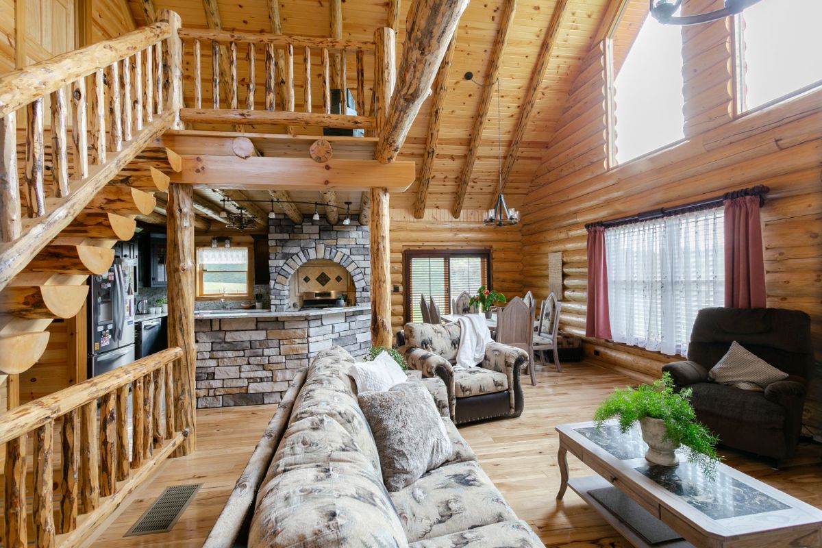 living room of log cabin with sofa in foreground and log staircase on left of room