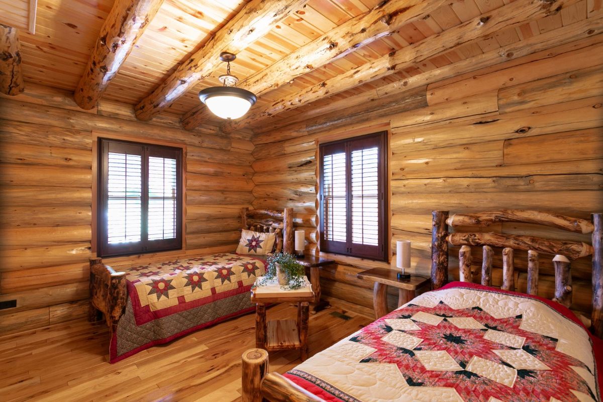 two twin beds in log cabin with rustic quilts