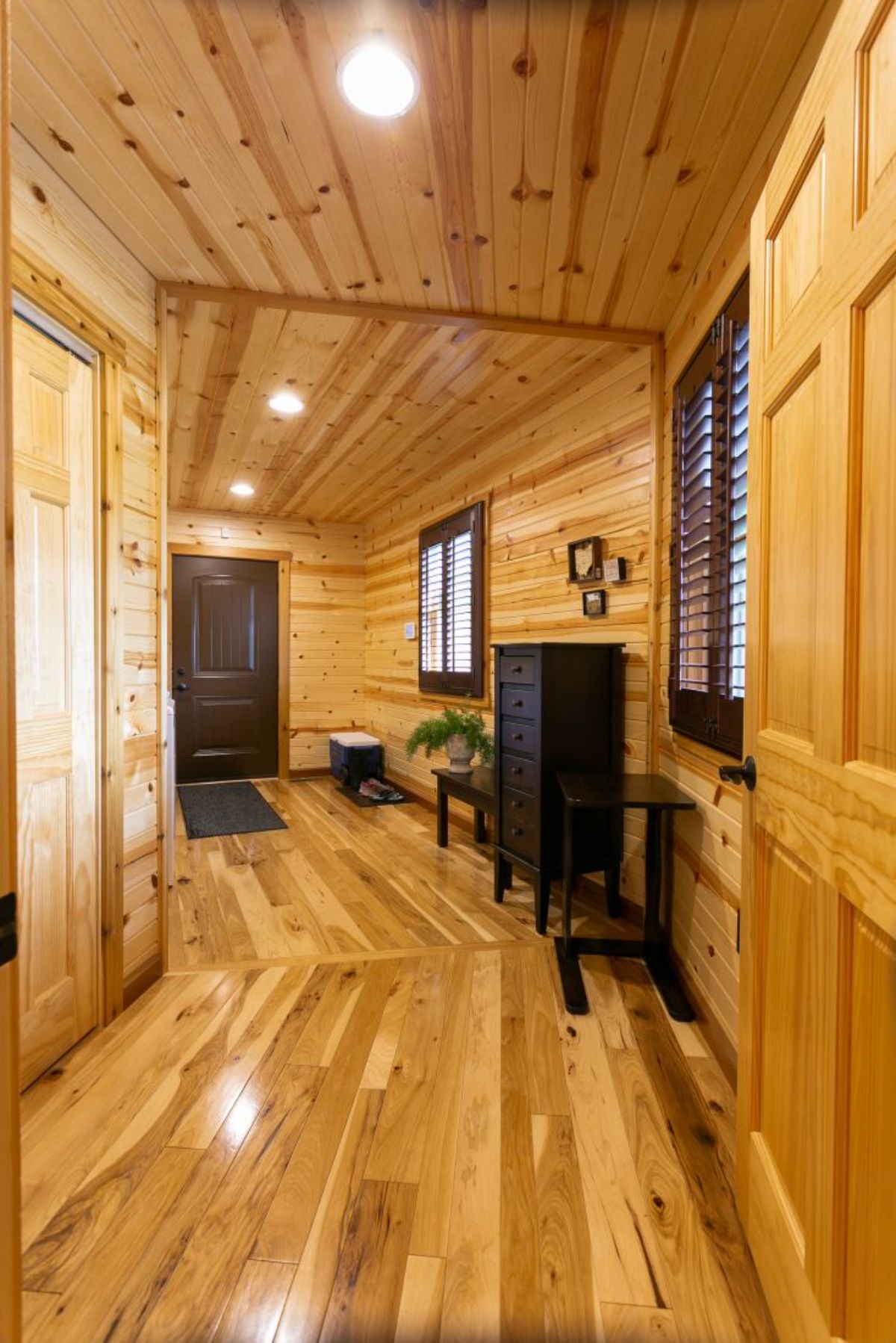 hall to front door with log and woodwork on walls floor and ceiling
