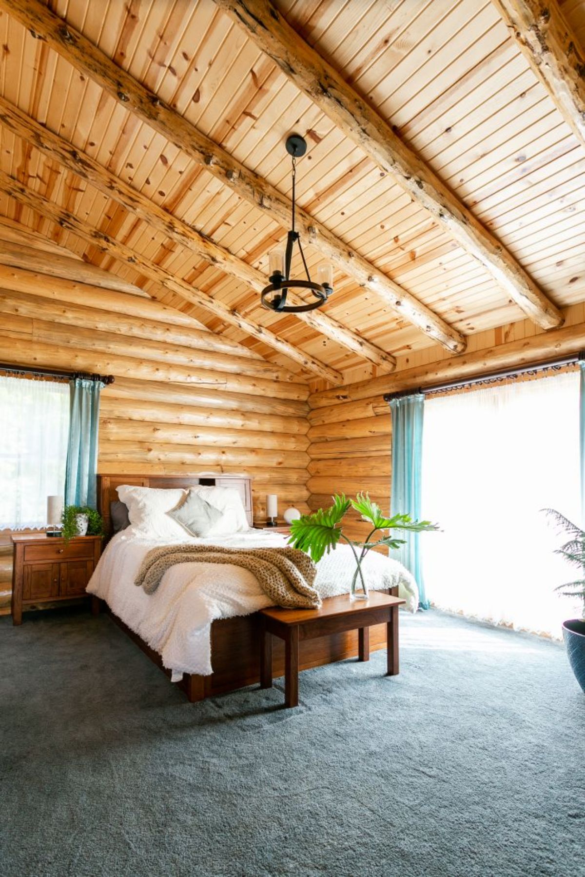 white bedding on bed in log cabin with glass doors
