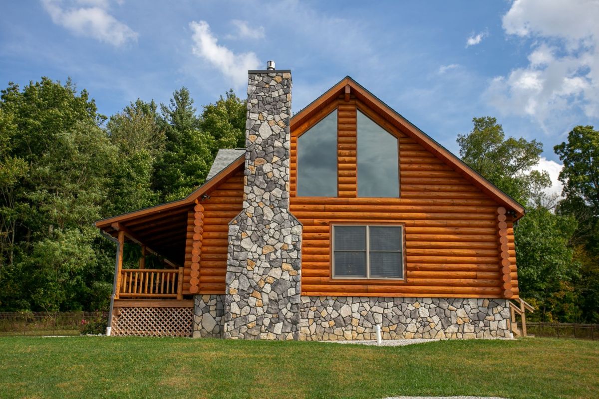 end of log cabin with stone chimney and stone base surround