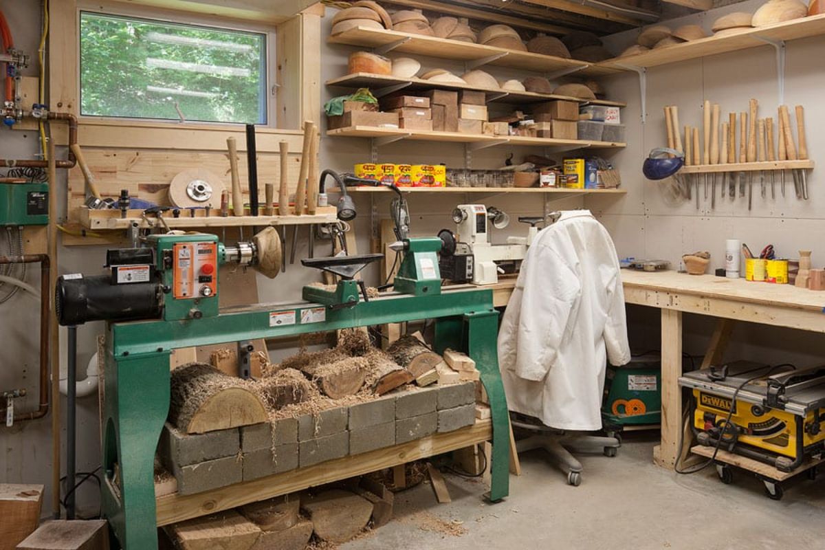 green work bench with many pieces of wood in shelves above