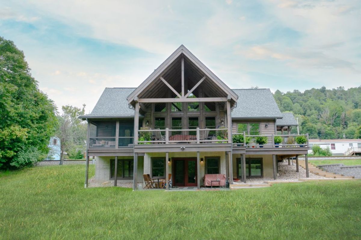 back side of log cabin with light grey wood and walkout basement