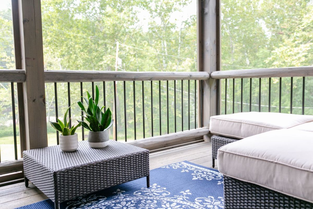 porch with railing and wicker furniture with light cream cushions