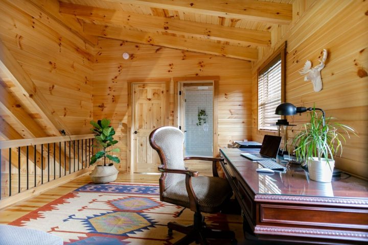 log cabin loft office with railing on left and desk on right