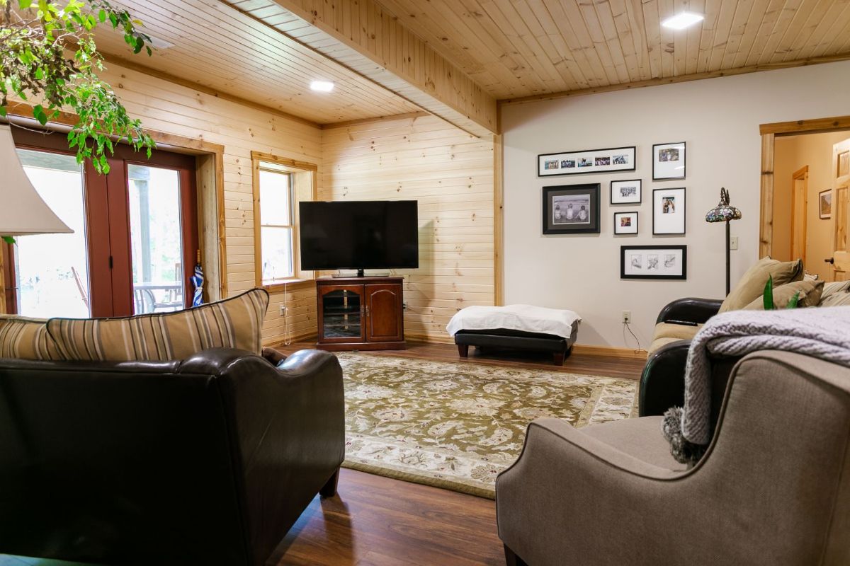 basement with door on left and sofas in foreground with wall of pictures in back right